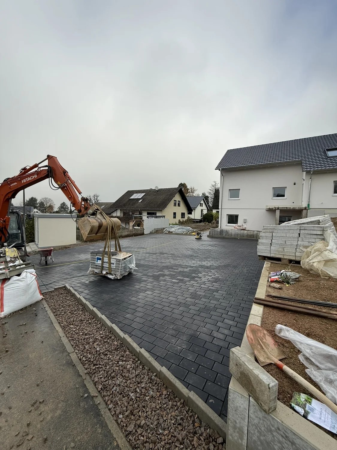 Pflasterfläche und Bagger auf einer Außenanlage